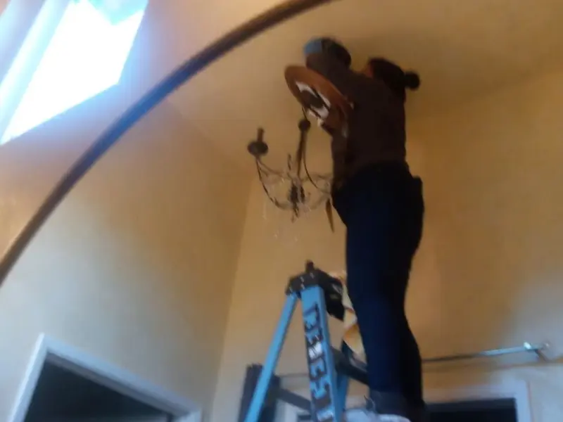 Electrician installing a chandelier in a Ocala residence